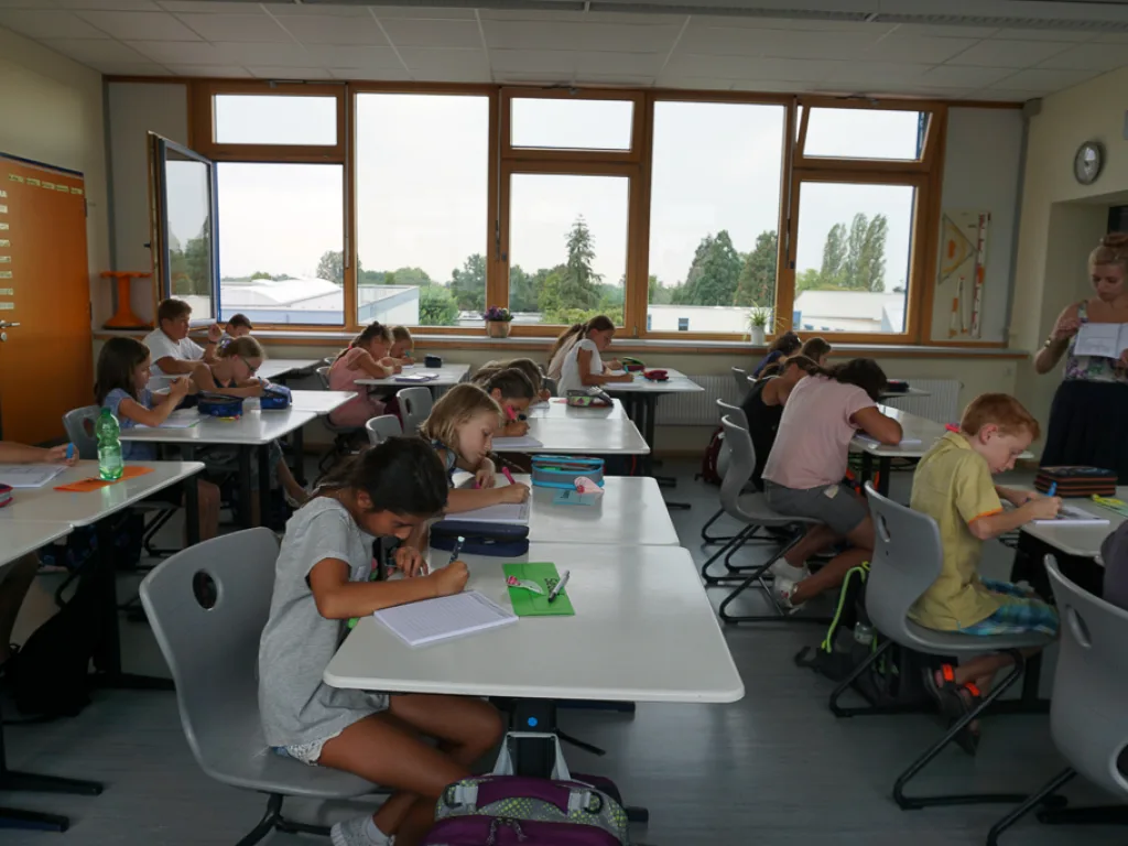 Kinder schreiben an ihren Plätzen.
